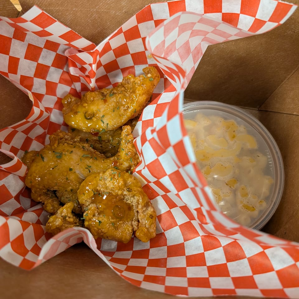 Cap Hill Burgers, Wings and Soul Food's fried chicken wings with mac and cheese in a takeout box.
