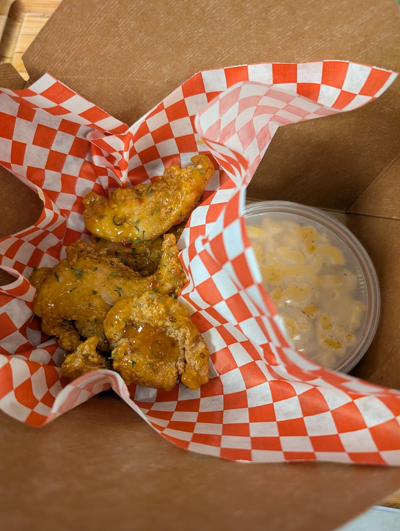 Cap Hill Burgers, Wings and Soul Food's fried chicken wings with mac and cheese in a takeout box.